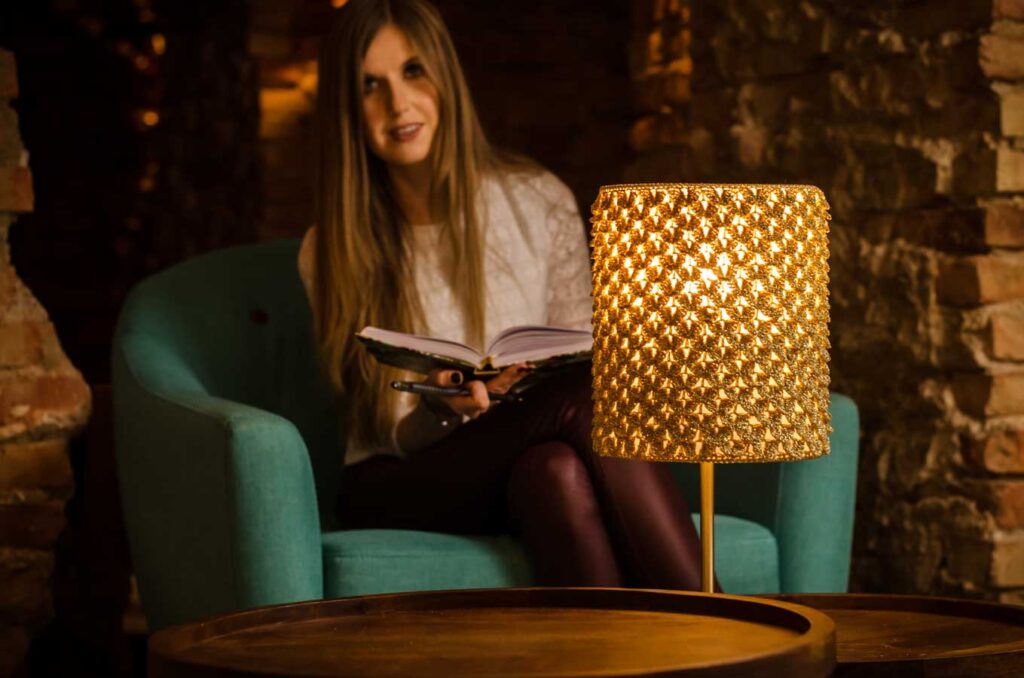 dziewczyna z książką, czyta przy złotej lampie zrobionej na szydełku